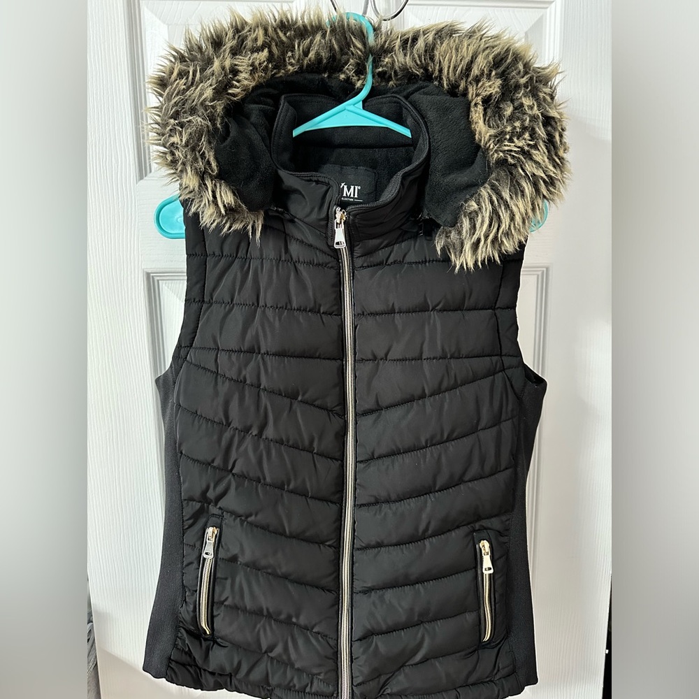 Women’s vest. Warm, black color, pockets have zippers, hood has imitation fur.